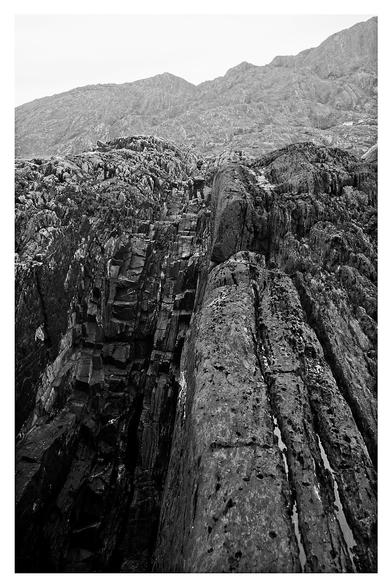 My friend M, almost hidden amongst the leading lines of the cut and eroded rock stretching and rising up from the sea. Behind is the ridge climb left to right.