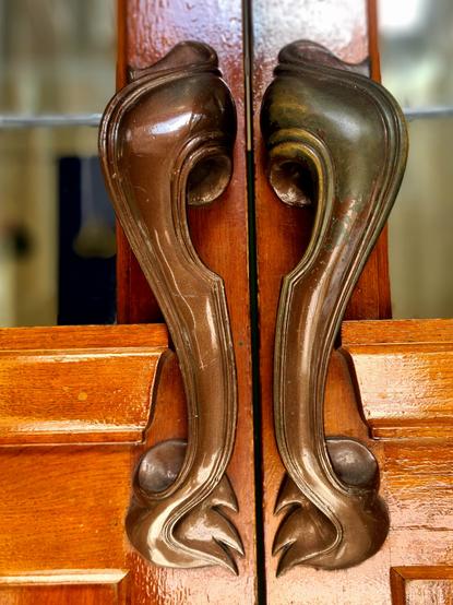 A pair of mirror-image curvaceous metal door handles.