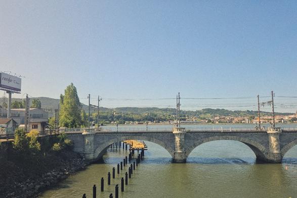 Crossing the border bridge between span and France. In front the railway bridge by SNCF/RENFE, in the back green hills. Blue sky.