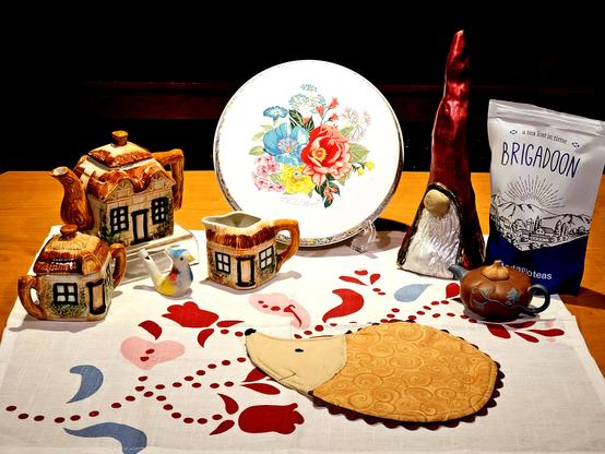 A tea tableau in warm tones incorporating elements of folk tales including hedgehogs, a gnome, thatched cottages, a pumpkin, folk art, and a black tea from Adagio called Brigadoon, after the legendary invisible village.