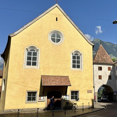 A yellow two  stories house with a pointed roof. Windows and front door awning positions make it looks like a big face.
