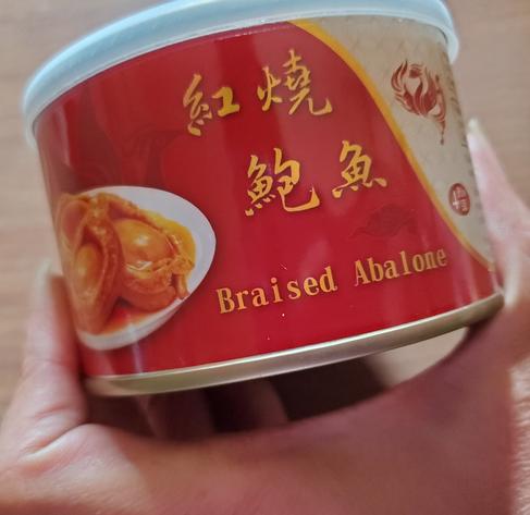 Braised abalone in a red tin with gold Chinese lettering.