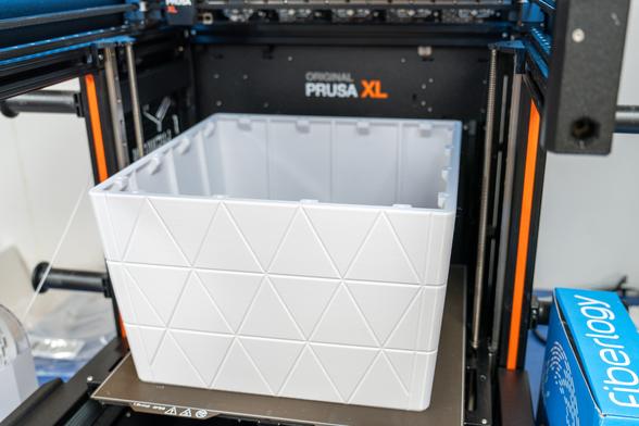 Photo of one part of the shell of a large 3D-printed planter. The printed part is white and is on the printing plate of a PrusaXL printer.