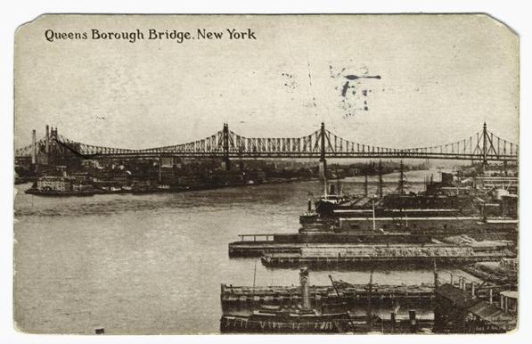 The image is a postcard depicting a black and white photograph of a bridge over a river, with a cityscape in the background. The bridge has a distinctive suspension structure with multiple cables supporting it. In the foreground, there's a boat on the waterway, and there are some buildings visible. The watermark "Queensborough Bridge" is visible at the top of the image, along with the word "NEW YORK". The postcard seems to be from a time when such imagery was common for commemorative or informational purposes. There's no text visible in the image that provides additional context or information.