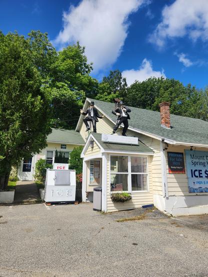 The side of a building that sells ice and spring water. On top of one portion of the roof are life size, performing Blues Brothers.