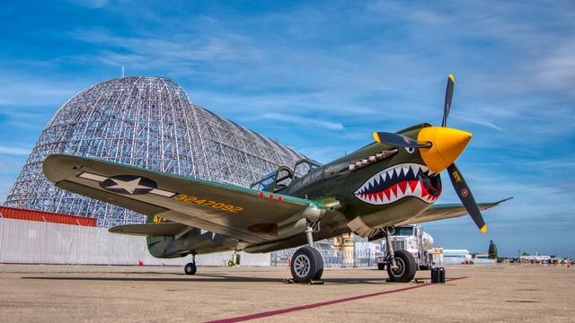 A p-40 Warhawk airplane sitting front of Hanger 1 at Moffett Field in California.