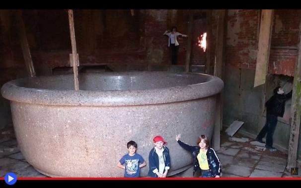 Enorme vasca di pietra in una sala in rovina, circondata da bambini e adulti per evidenziarne le dimensioni spropositate.