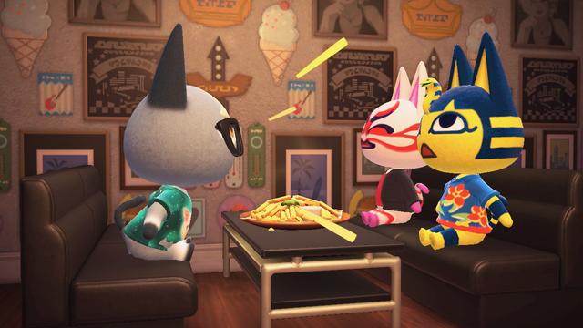 Animal Crossing: New Horizons screenshot. Image showing a diner scene with Raymond sitting in a booth talking loudly on one side of the table and laughing Kabuki on the other side next to Ankha in a different diner booth. A plate of fries is on the table in front of them.