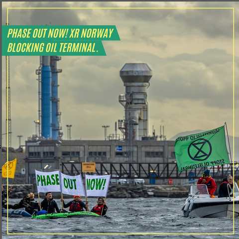 Image of an oil processing terminal in coastal Norway, at Kårstø. In front of it, floating, are a boat with an XR Norway flag saying 'Stop Oil exporation' and a number of kayaks holding a banner with "Phase Out Now"