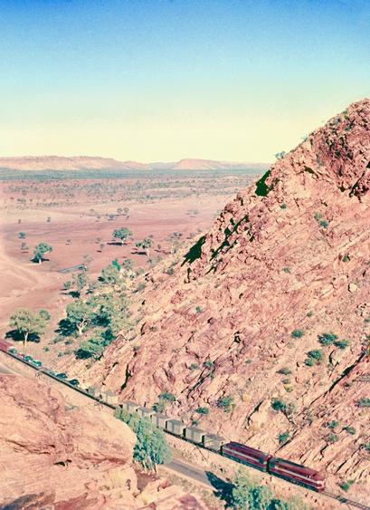 “Northbound train on the Central Australia Railway at Heavitree Gap, on the southern border of Alice Springs, Northern Territory, Australia. The train is hauled by two Commonwealth Railways NSU class diesel-electric locomotives”

source https://commons.m.wikimedia.org/wiki/File:Anton_Faymann_041_Auto_Colour.jpg#mw-jump-to-license