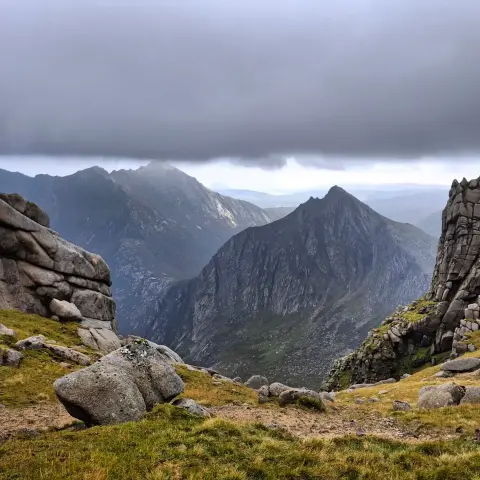 The finest view in Scotland! The pyramid of Cir Mhor, dark, vertical and foreboding, framed by the rock walls of Caisteal Abhail's tors. In the far distance, the ridge and summit of Goatfell is skimmed by heavy cloud.