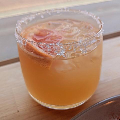 A Paloma cocktail with salted rim and garnished with a grapefruit slice