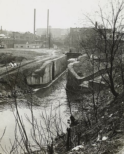 Black and white image from 1947, photographer Andre Kertesz, white horse and rider galloping along the Ohio & Erie Canal towpath near north Lock 2, Akron, Ohio, USA.