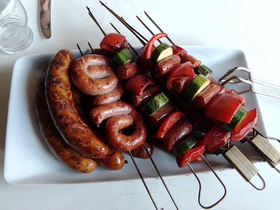 Eine weiße Porzellan Platte mit Grillgut:
- Chili Cheese Würste
- Bratwurstschnecken
- Chorizo Spieße
- Merguez Spieße
