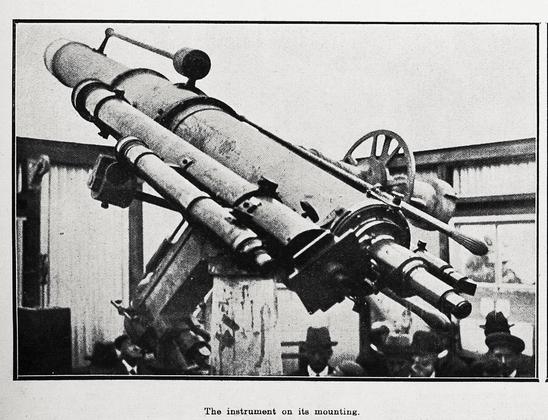 Black-and-white photo: The instrument on its mounting. 1924. Description: A view from behind of Wellington City Council’s new 9-inch telescope in Kelburn. Its temporary installation was opened to public view last week, and the heads of some people can be seen in the photo, all wearing hats. Citation: Supplement to the Auckland Weekly News, 4 September 1924, p. 42. Auckland Libraries Heritage Collections AWNS-19240904-42-06. https://kura.aucklandlibraries.govt.nz/digital/collection/photos/id/245935