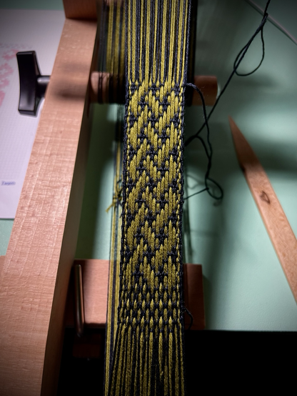 The start of a narrow band with a green Celtic knot pattern on black background