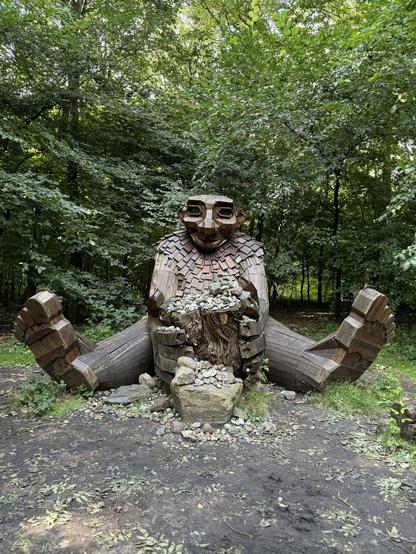 A wooden troll sitting in the woods with good luck stones in his hands