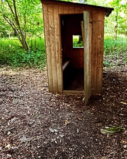 Eine kleine Holzhütte mitten im Wald. Ähnelt einer kleinen Verkaufshütte auf einem Weihnachtsmarkt