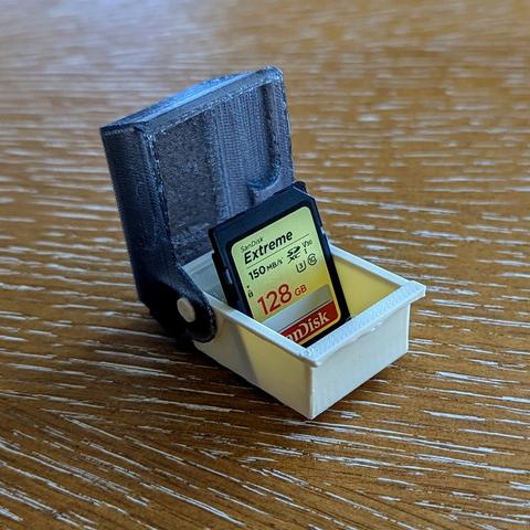 A photo of a miniaturized floppy disk organizer holding a SD card.