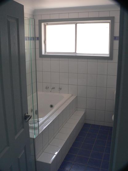 Same view as second image through the door looking left - this time of the renovated bathroom.  Tiles continue around the walls. The spa bath now has a tiled surround and step, matching and aligning with those on the walls. Sib was near OCD about details. The edge of a glass frameless shower can just be seen at left. It was the only bit my sibling didn't do in this room - the shower quotes came with installation included. He did pay a lot of attention to how it was done - the installer was an expert with methylated spirits and silicon, spraying and wiping away excess with deft movements.