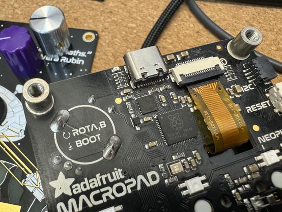 The rear of a macropad, showing a ribbon tape curling in to a connector.