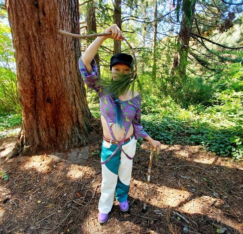 Me, standing by a fir tree, holding up a ponderosa pine tree fallen branch over my face, like a beard.