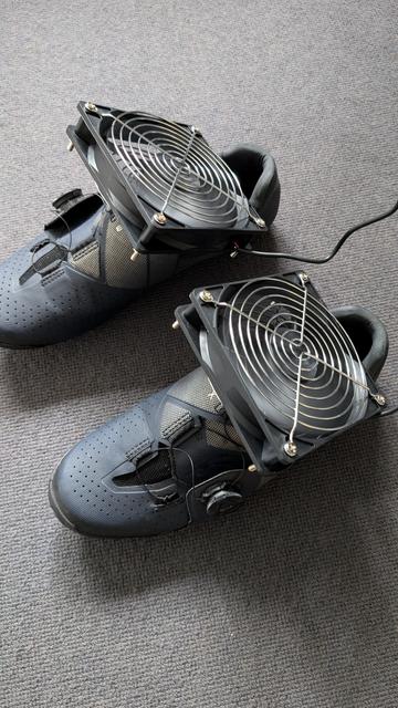 Zu sehen sind ein paar Fahrradschuhe, darauf liegen zwei PC-Lüfter.