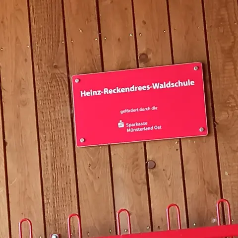 Braune Holzwand mit roten Sponsorenschild