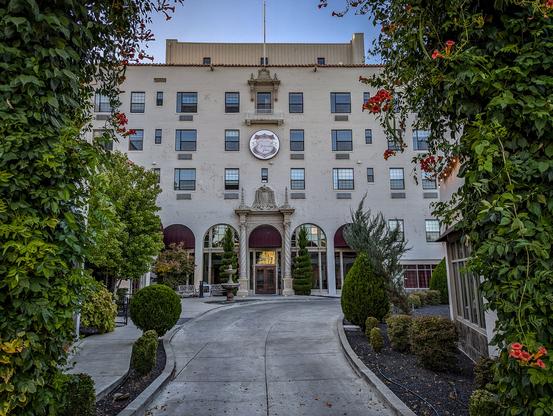 View of the courtyard and hotel five-story building of the historic Oroville Inn.
"The Oroville Inn is a five-story building (including interior mezzanine) with two attached one-story retail shop wings, all located on a large corner lot in the downtown business district of Oroville, California. Its exterior design follows the late 19th and early 20th century Spanish Colonial Revival style popular in California during that period. The hotel was dedicated on June 1, 1930. Because of its impressive dimensions and modern conveniences, the Oroville Inn immediately became the entertainment and social center of the area. Still in use and recently restored with meticulous attention to detail, the Inn survives today as the tallest hotel in California north of Sacramento. There have been no alterations, additions, or other changes that have affected the historic integrity of the property.
Although the Great Depression descended across the nation just as the Inn was completed, Oroville continued to be a prosperous and busy place because the gold dredging industry here was at its height, and construction of the new Feather River Highway from Oroville to Reno was just getting underway and was not abated. Considered the finest hotel along the highway between Marysville and Reno, with private bath in every room."