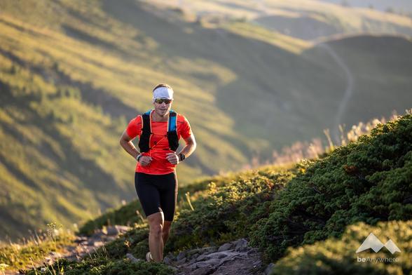 Falko Burghausen, a man doing a trail run in the mountains of Switzerland and wearing black shorts and a red shirt.