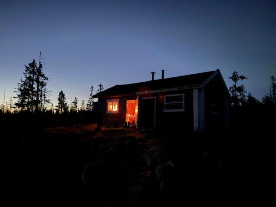 Seterhytte i skumringen. Lys i vinduet