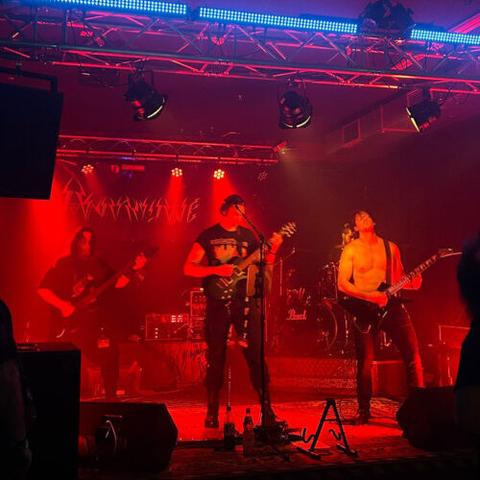 Foto der Band auf der Bühne in Leipzig. Alles ist in rotes Licht getaucht.