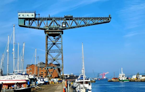 A massive titan crane towera over the yachts in a scottish marina.