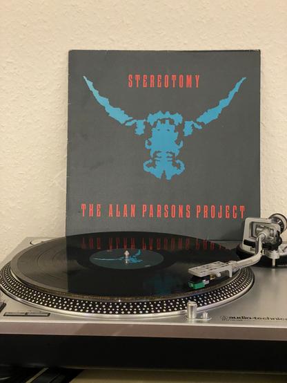 The album cover of „Stereotomy“, an Alan Parsons Project Album. On the bottom of the picture is a turntable playing the vinyl.
