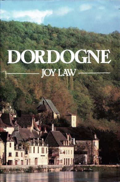 A book about the Dordogne region of France, simply entitled 'Dordogne'. The author is Joy Law. Cover image is a photograph of riverside scene shows old stately buildings with a high forested hill behind them. Green trees, blue sky and a few clouds.