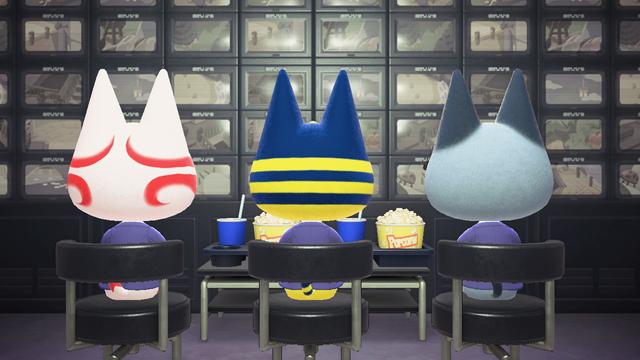 Animal Crossing: New Horizons screenshot. Image shows three chairs from behind with cats (Kabuki, Ankha, and Raymond from left to right) sitting in them watching a wall full of monitors. In front of them is a small table with popcorn and drinks on it.