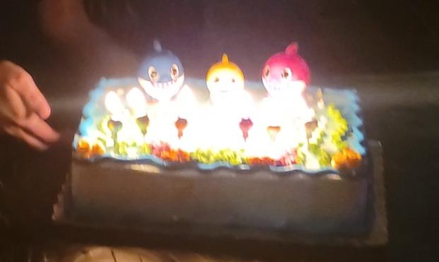 Demonic looking baby shark birthday cake with candles and flames