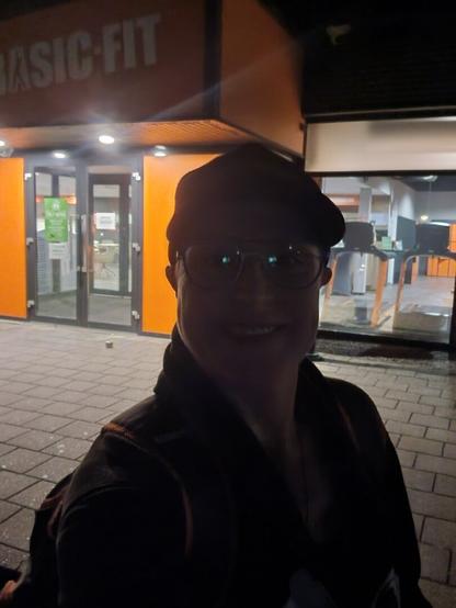 Selfie in front of the Basic-Fit during night time. My face is darker, the entrance of the gym is better visible.