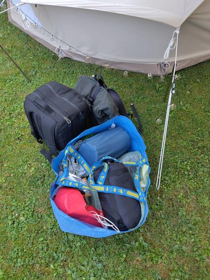 Three pieces of luggage are lying on the ground near a tent.