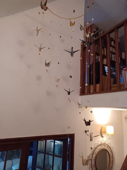Dans une mezzanine grande suspension en origami avec des grues bleues et or et des étoiles de la chance