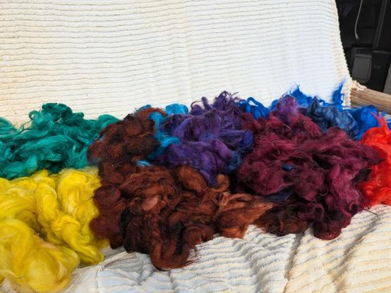gefärbte Wollflocken in gelb, türkis, violett, dunkelrot, feuerrot und blau
