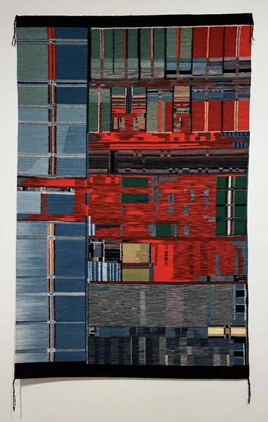 A Navajo rug representing an AMD processor chip. This weaving has large rectangular regions. The colors include bright red, two shades of blue, and green.
