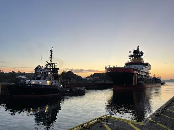 Schlepper Wulf 7 vorne links und das neue Mehrzweckschiff rechts fahren in die Kieler Schleuse ein.