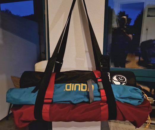 Tasche mit aufgeschnalltem Equipment, aufgehängtan den Tragegurten.