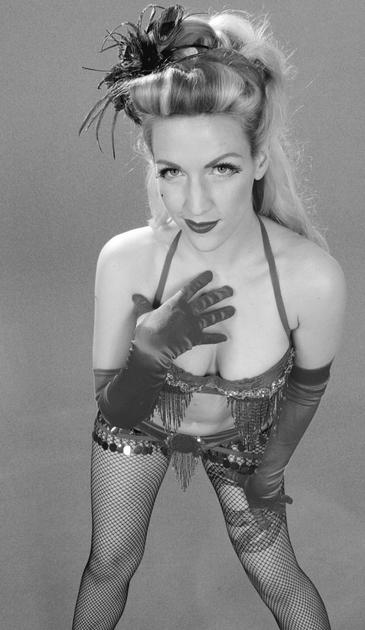 Monochrome portrait of Melody Mangler in one of her burlesque outfits. Sequin bikini with fringes, fishnet stockings & long satin gloves with a half updo pinup hairstyle.