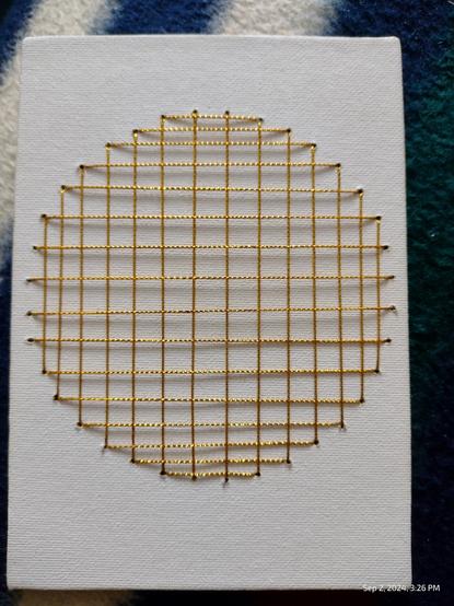 White A5 canvas with circular geometric pattern made up of lines to form a circle. Lines are Golden Metallic Embroidery Thread