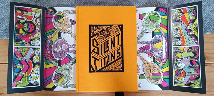 The book without its jacket: inside the cover is yellow-orange and the title is printed over a rugged clothlike texture. The interior of the jacket shows a map and some figurines.
