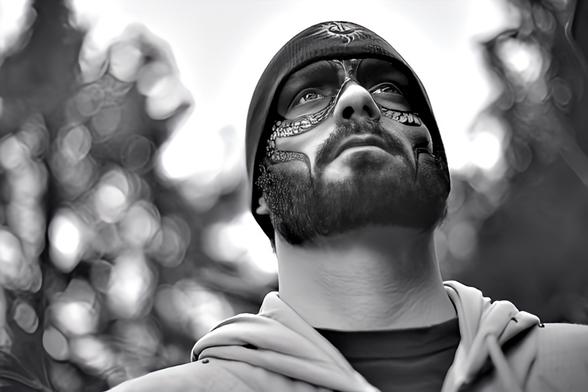 A portrait of a bearded man wearing a toque & snake like face paint designs.
Black and white photo.