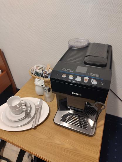 Foto aus dem Hotelzimmer in Münster mit einem Kaffeevollautomaten und Espressotassen auf einem Beistelltisch neben dem Bett