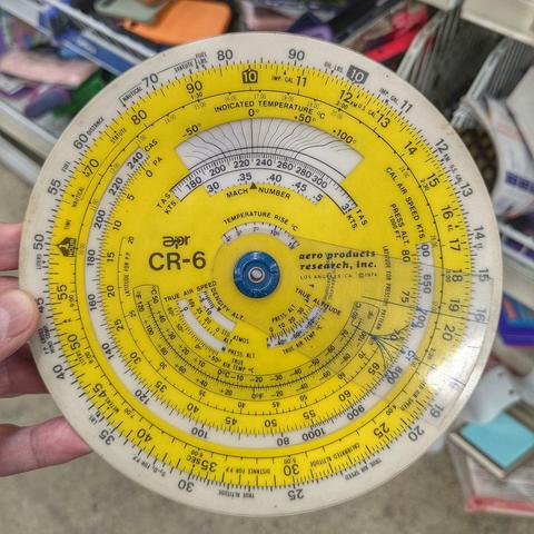 Yellow and white circular slide rule Aero Products CR-6, specialized for aviation calculations like true air speed and altitude, fuel consumption, wind solutions and lots more.